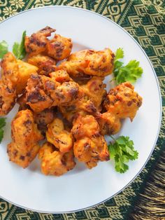 a white plate topped with chicken wings and parsley on top of a green table cloth