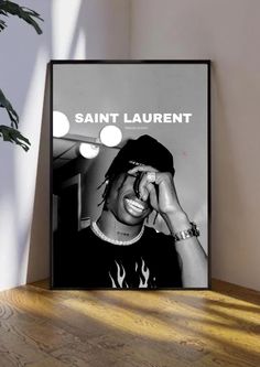 a black and white photo with the words saint laurent on it, sitting next to a potted plant