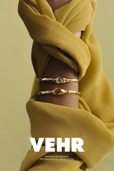 a woman with her arm wrapped in a yellow scarf and wearing gold bracelets that read, vehr