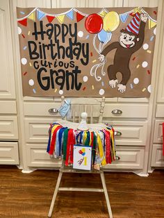 a birthday sign with a monkey on it in front of a party backdrop that says happy birthday curious grant