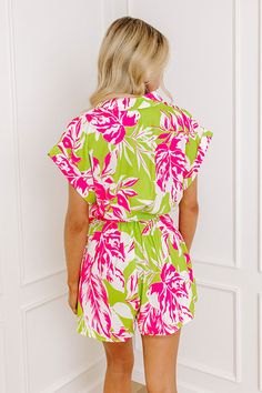 - Get your piña coladas ready and relax under the sun in this adorable romper! - Unlined material with a pink and green hued abstract botanical print - A collared neckline - A button down bodice - Short sleeves with rolled cuffs - An elastic waistline with a removable tie closure belt - A relaxed romper silhouette that ends in a upper-thigh length hemlines Green Tropical V-neck Jumpsuits And Rompers, Green Tropical Print Jumpsuits And Rompers For Spring, Green Beachwear Jumpsuits And Rompers For Day Out, Spring Beach Green Jumpsuits And Rompers, Summer Floral Print Jumpsuits And Rompers With Short Sleeves, Green V-neck Tropical Print Jumpsuits And Rompers, Summer Floral Print Jumpsuit With Short Sleeves, Summer Floral Print Short Sleeve Jumpsuits And Rompers, Green V-neck Tropical Print Jumpsuit