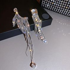 a pair of earrings that have been made out of crystal beads and are hanging from a black box