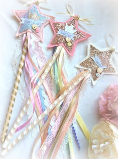 several different colored stars and ribbons on a white surface with pink carnations in the foreground