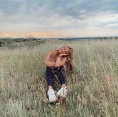 a woman sitting in the middle of a field with her head on her hands and eyes closed