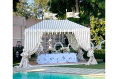 a white tent with curtains next to a swimming pool