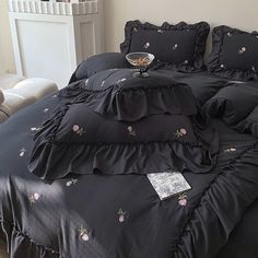 a bed with black ruffled bedspread and pillow cases on top of it