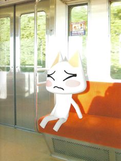 a white cat sitting on top of an orange bench next to a glass door with trees in the background