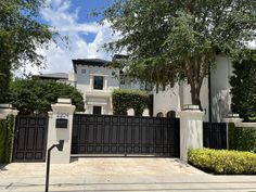 a white house with black gate and trees