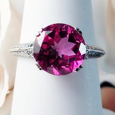 Set with a mesmerizing 3-carat natural pink topaz gemstone, the round full-cut stone measures 10mm in diameter (3/8th"). Its radiant hue is accentuated by the intricate silver filigree setting, adorned with delicate leaf motifs cascading down each side of the band. Pink Topaz Ring, 1930's Style, Vintage Revival, Nature Ring, Ring Art Deco, Pink Topaz, Button Ring, Deco Ring, Art Deco Ring