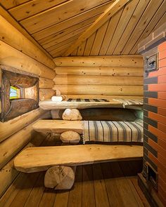 the inside of a log cabin with beds and benches on each side of the room