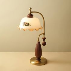 a lamp that is sitting on top of a table with a wooden base and white glass shade