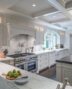 a large kitchen with white cabinets and marble counter tops, an island in the middle