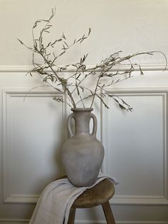 a vase with some branches in it on a stool