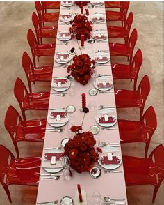 a long table with red chairs and white plates on it is set for a formal dinner