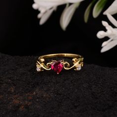 a close up of a ring on a rock with flowers in the background