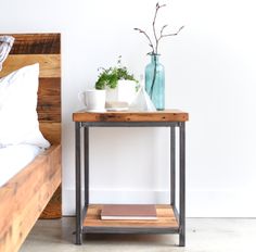 a small table with some plants on it and a bed in the background next to it