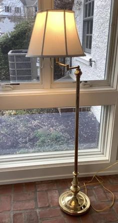 a lamp sitting on top of a window sill next to a brick floor in front of a window