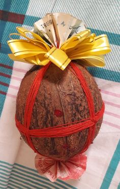 a piece of fruit wrapped in red string and tied with gold ribbon on top of it