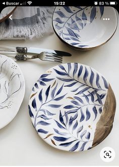 plates and utensils are laid out on a table with blue leaves painted on them