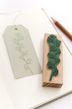 a wooden stamp with a green leaf on it next to some pencils and paper