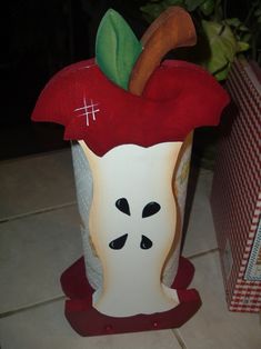 an apple shaped vase sitting on top of a tile floor next to a red and white box