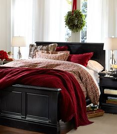 a bed with red blankets and pillows in a bedroom