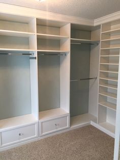 an empty walk in closet with white shelving and shelves on the wall, carpeted floor