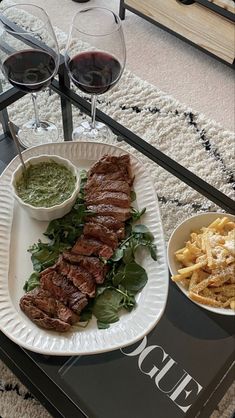 there is a plate with steak and french fries on it next to two glasses of wine