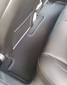 the interior of a car with grey leather seats and gray floor mats, including an arm rest