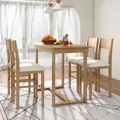 a dining table with four chairs and a bowl of fruit on the table next to it