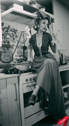 a woman sitting on top of an oven in a kitchen