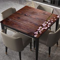 a wooden table with chairs around it and flowers painted on the top, in front of a bookshelf