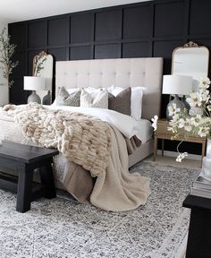 a bedroom with black walls, white bedding and an upholstered headboard