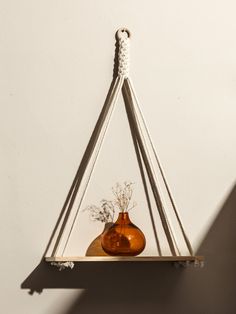 two brown vases sitting on top of a wooden shelf next to a white wall