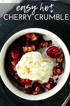 a bowl filled with fruit and ice cream on top of a black plate next to a spoon