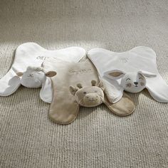 three bibs laying on the floor with one stuffed animal in it's mouth