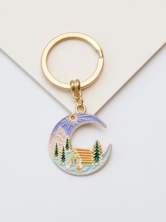 a keychain with a house on the moon and trees painted on it's side