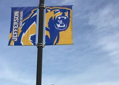 a blue and yellow flag on top of a pole next to a street sign that reads jefferson university