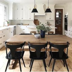 a kitchen with white cabinets and black chairs is pictured in this image, there are several lights hanging from the ceiling