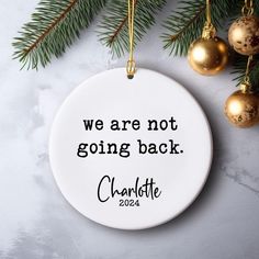 we are not going back christmas ornament on a white background with gold ornaments