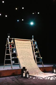 the stage is set up with ladders and an open sheet of paper on it