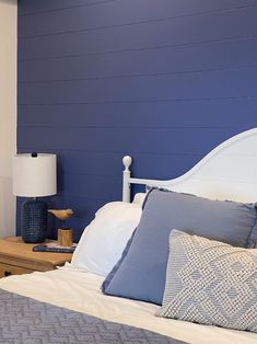 a bedroom with blue walls and white bedding, two night stands on either side