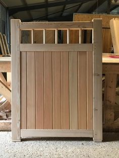 a wooden gate sitting on top of a floor next to a pile of wood planks