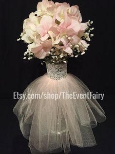 a vase filled with pink flowers on top of a black table next to a veil