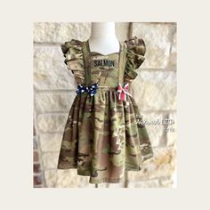 TURN AROUND TIME Due to the number of orders, the current turnaround time is 5 weeks, this means it will ship from me 5 weeks from the date of purchase plus the time of shipping. Please consider this when ordering. Handmade in Texas with authentic military fabric. This military dress can be made in Army, Air Force, Marine, and Navy camo, it comes with ruffle sleeves as well as stars and stripes bows on the front. The dress comes with a sweetheart bodice and adjustable tie-back straps. The dress includes personalized embroidered name tape at no additional charge. The name will come in ALL CAPS, if you have a name that has a lowercase letter please let me know in the comments during checkout.  This item has serged seams for durability and a professional finish. Wash instructions: Turn the it Baby Homecoming Outfit, Baby Homecoming, Deployment Homecoming, Military Dress, Homecoming Outfit, Military Homecoming, Military Dresses, Navy Camo, Military Kids