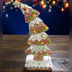 a christmas tree made out of cookies on a wooden table with lights in the background