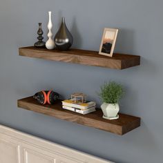 two wooden floating shelves in the corner of a room with pictures and vases on them