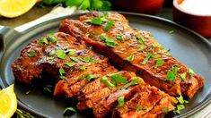 two pieces of meat on a plate with lemons and parsley