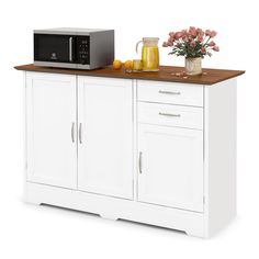 a microwave oven sitting on top of a white cabinet next to a vase with flowers