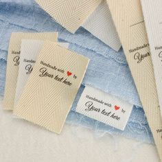 three tags with names on them are laying next to each other and some blue fabric